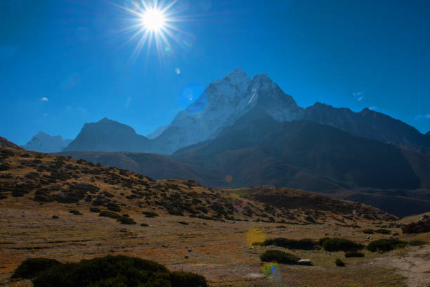 クンブ、ネパールのエベレストベースキャンプトレッキングルートに太陽フレアと美しい雪が山を傷つけました - scarped ストックフォトと画像