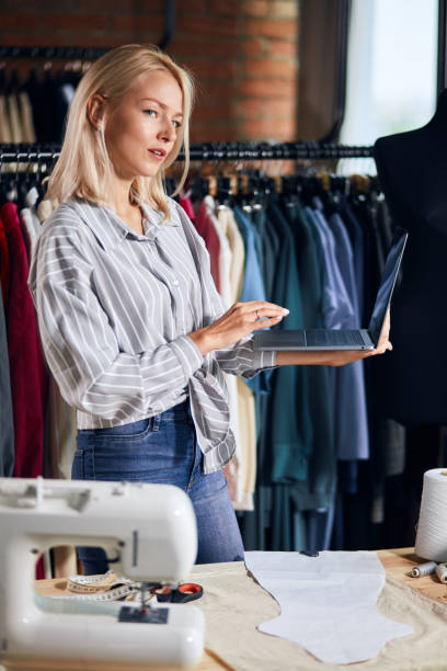 istock pleasant tailor working with laptop, standing behind the table 1176958716