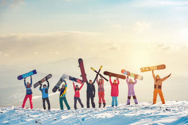 Happy friends skiers and snowboarders at ski resort Big group of happy friends skiers and snowboarders having fun and holding ski and snowboards on mountain top snowboarding stock pictures, royalty-free photos & images