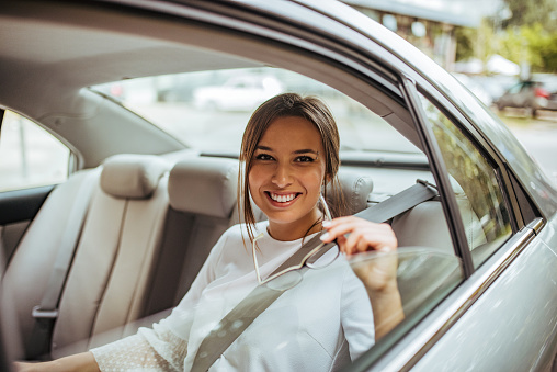 Portrait of a smiling young businesswoman traveling to work by a car.