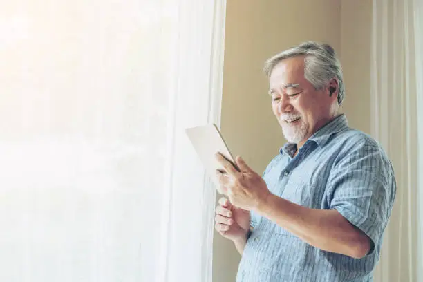 Senior Male using a smartphone , smiling feel happy in bedroom at home - lifestyle senior concept