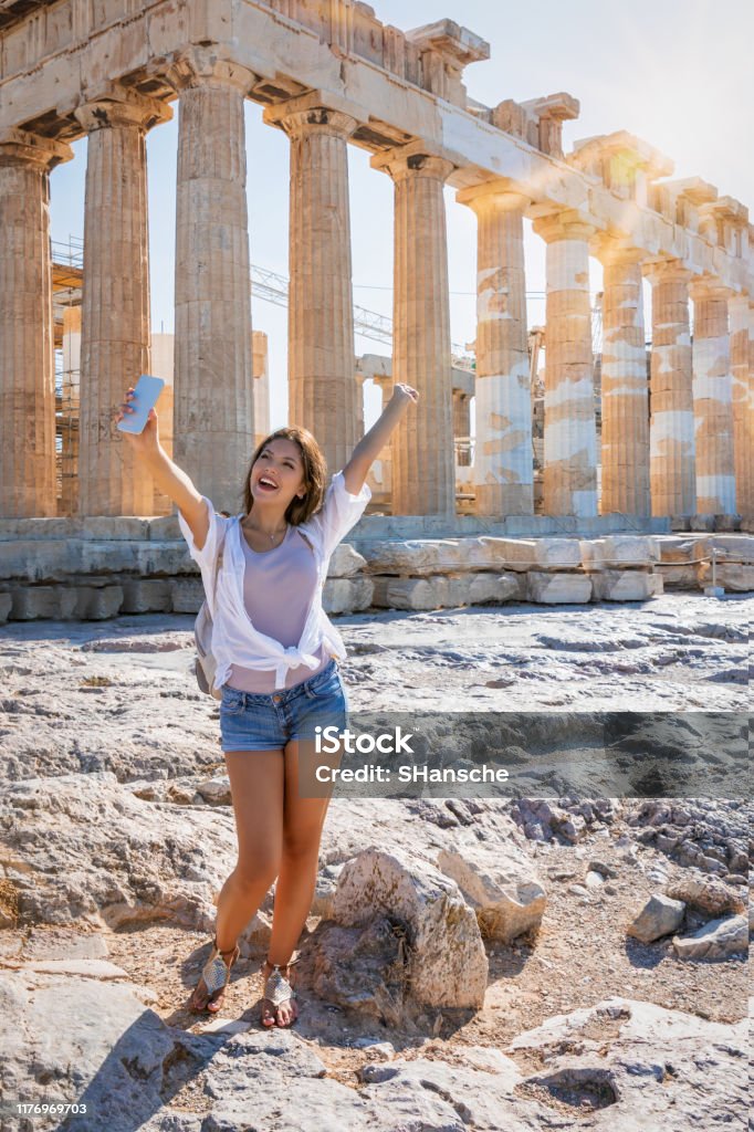 Woman takes selfie pictures in front of the Parthenon Temple at the Acropolis of Athens, Greece Happy female traveler woman takes selfie pictures with her mobile phone in front of the Parthenon Temple at the Acropolis of Athens, Greece Selfie Stock Photo