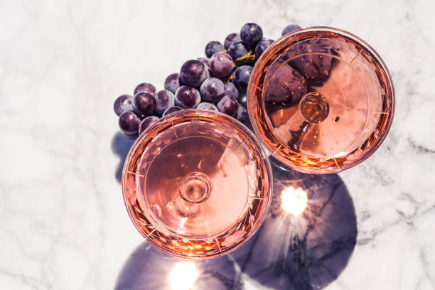 Two crystal stemmed glasses with rose wine Two crystal stemmed glasses with rose wine on marble table outdoors in a cafe. Aperitif and relax time cafe transparent glass table stock pictures, royalty-free photos & images