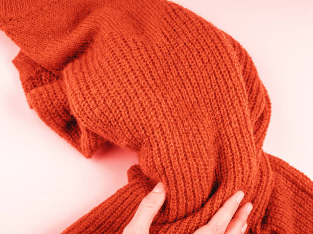 istock Orange sweater on pink with woman's hand 1176972325