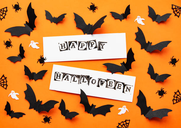 holidays  concept - halloween paper decorations and sweets with blank copy space over orange background