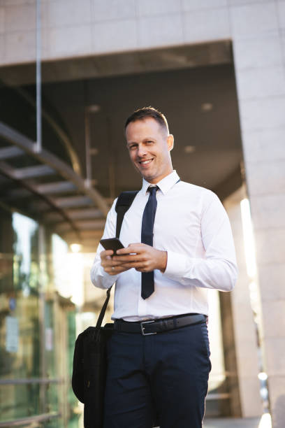 istock Businessman reading text message on mobile phone outdoors 1176975780