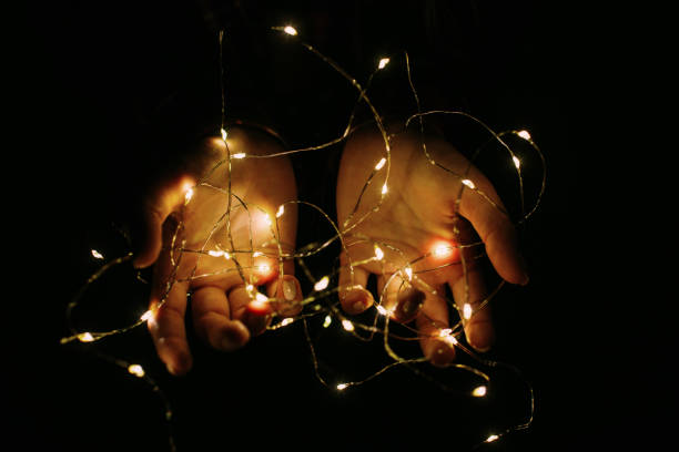 istock Christmas lights shining warmly in female hands. 1176976344