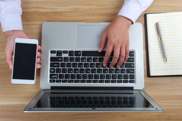 istock Businesswoman hand using laptop computer with mobile phone 1176977282