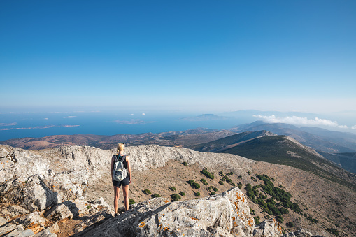 Young woman standing on the top of Mount Zas, which is the highest point in the Cyclades (Naxos island, Greece).