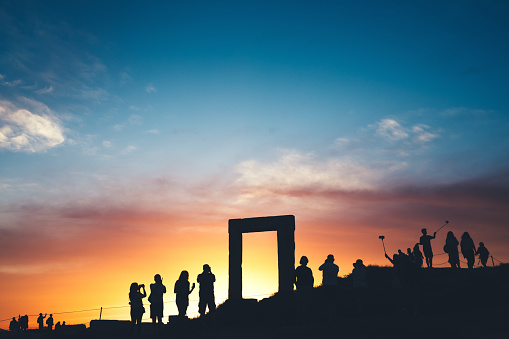 Tourists taking photos of Temple of Apollo - Portara (Naxos island, Greece).