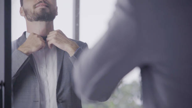 istock Man in formal suit getting dressed in dressing room for work or wedding. 1176978578