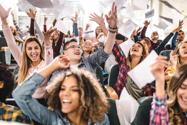 istock Cheerful college students having fun while throwing papers in the classroom. 1176986083
