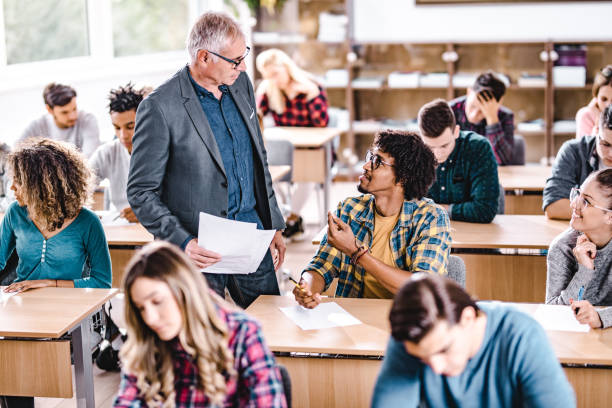 istock Happy black student talking to senior teacher on a class in the classroom. 1176986506