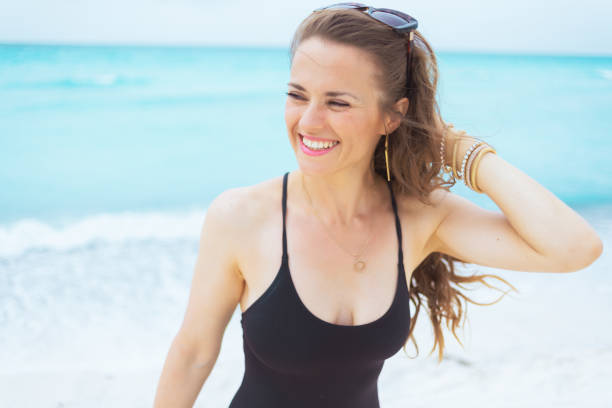 istock smiling young middle age woman on white beach looking aside 1176987114