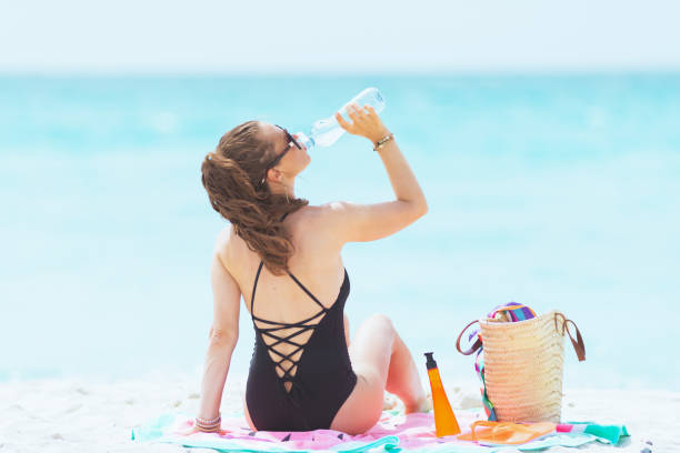 istock 40 year old woman drinking water while sitting on round towel 1176987442
