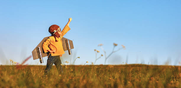 Child pilot aviator with wings of airplane dreams of traveling in summer  at sunset Child pilot aviator with wings of airplane dreams of traveling in summer in nature at sunset imagination stock pictures, royalty-free photos & images