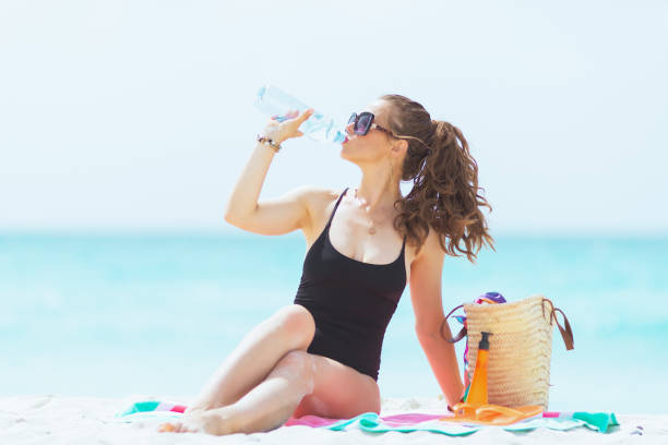istock middle age woman drinking water while sitting on round towel 1176987541