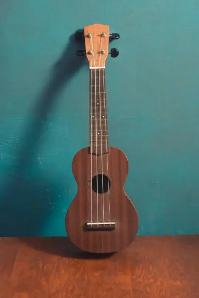 ukulele on wood with isolated blue background, front view