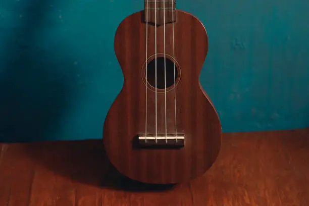 ukulele in front view on wood with isolated blue background, close up