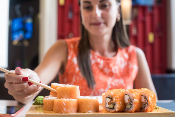 istock Female in cafe eats sushi with chopsticks. Sushi closeup. selective focus 1176989024