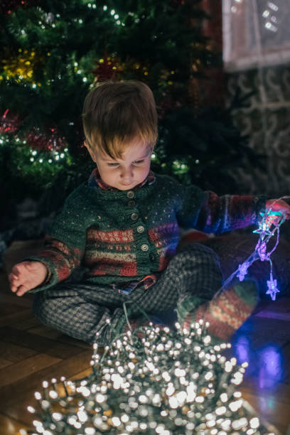 istock Little boy playing with Christmas lights at home 1176990953