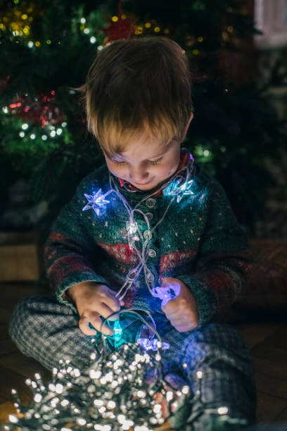 istock Little boy playing with Christmas lights at home 1176990956