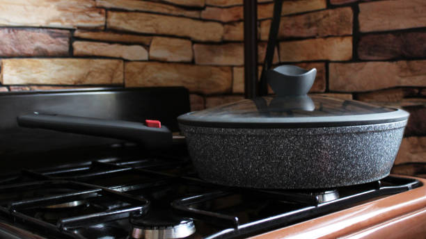 istock frying pan on the brown gas cooker, brick background 1176991178