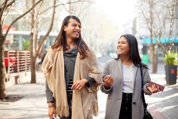 She always has juicy stories to tell Cropped shot of two affectionate young friends having a discussion while walking in the city transgender person photos stock pictures, royalty-free photos & images