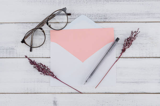 istock Blank pink card in white envelop, eyeglasses and black pen 1176993025