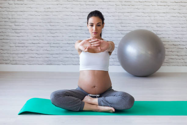 una mujer embarazada muy joven estirando después de hacer ejercicios de pilates en el aula de preparto. - human pregnancy yoga exercising prenatal care fotografías e imágenes de stock