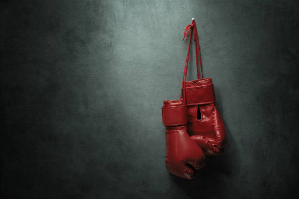 Boxing gloves hanging on the wall Pair of boxing gloves hanging nailed to the wall with copy space boxing glove stock pictures, royalty-free photos & images