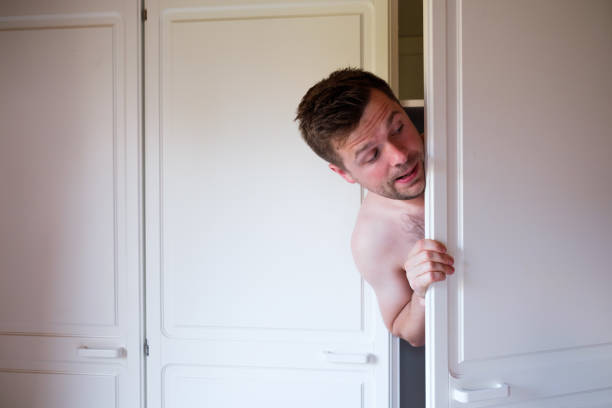 istock Young caucasian naked man hiding in wardrobe 1176997370