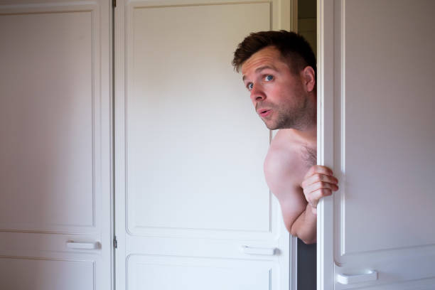 istock Young caucasian naked man hiding in wardrobe 1176997406