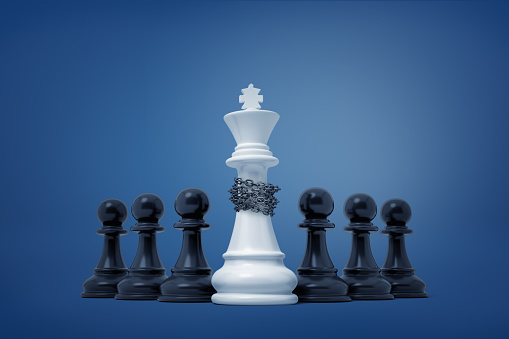 3d rendering of a group of black pawns which have taken captive and enchained a white king piece. Surrender and defeat. Winning and losing. Victory and triumph.