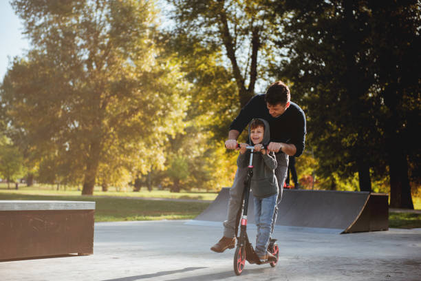 istock Little boy riding a push scooter with his dad 1177001291
