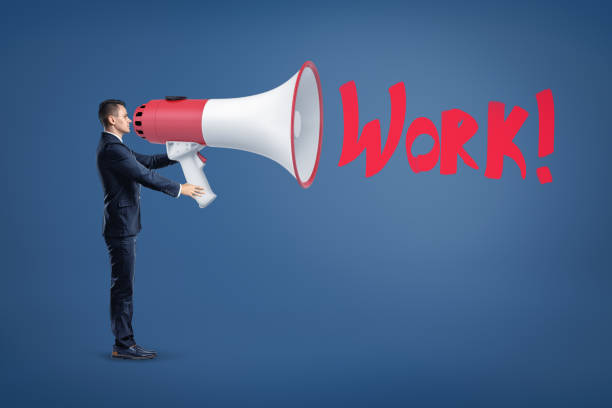 istock Businessman with big megaphone and red 'WORK' sign on blue background. 1177001404