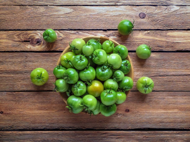 istock Green tomatoes in a bowl on a wooden table. 1177004410