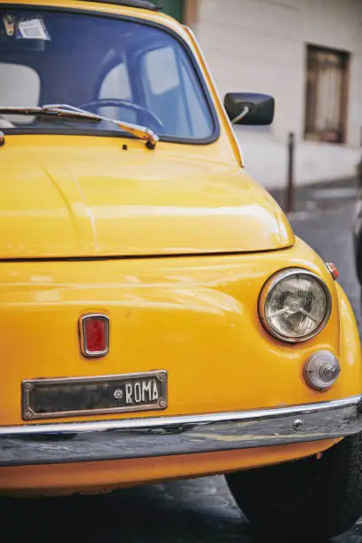 Detail view of an old Fiat 500 car typical of Italy in yellow color parked