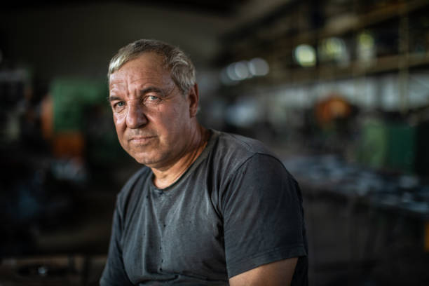 Portrait of mature manual worker in metal industry Portrait of mature manual worker in metal industry, sitting on table and looking at camera maintenance engineer photos stock pictures, royalty-free photos & images