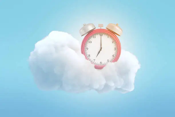 Photo of 3d rendering of an old-fashioned alarm clock on a fluffy white cloud on a blue background.