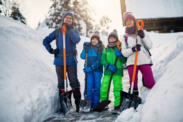 Father with kids cleaning snow with shovels