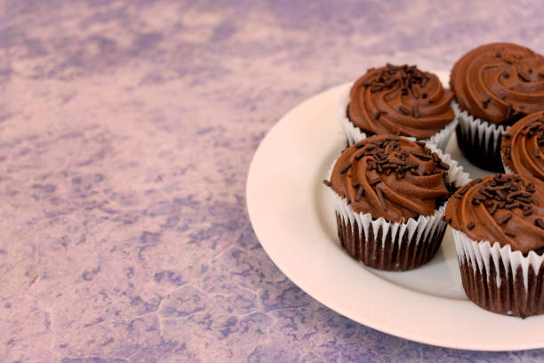 istock Chocolate cupcakes over white plate and purple blurred background with copy space 1177021062