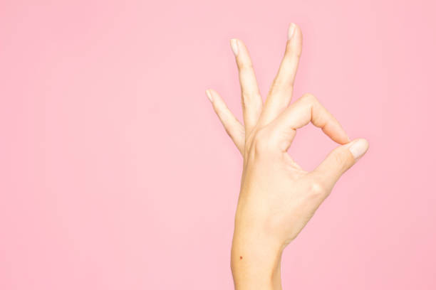 Female hand or hand of a woman showing number three or showing the ok sign with pink background Female hand or hand of a woman showing three fingers and giving the ok or good or approved sign, or showing the number three with a pink background pink promise stock pictures, royalty-free photos & images