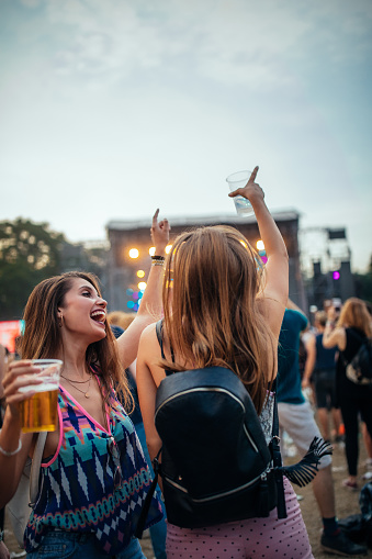 Two female friends drinking beer and having fun at a festival