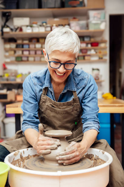istock Senior female potter working on pottery wheel while sitting  in her workshop 1177025334