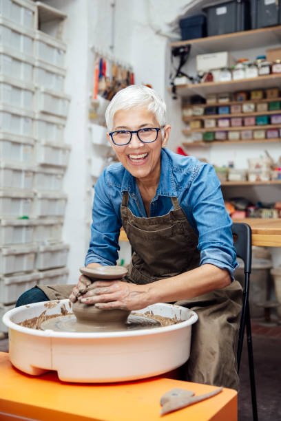 istock Senior female potter working on pottery wheel while sitting  in her workshop 1177025423