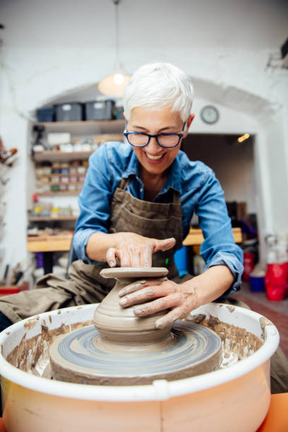 istock Senior female potter working on pottery wheel while sitting  in her workshop 1177025424