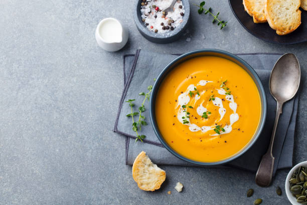 Pumpkin, carrot cream soup in a bowl. Grey background. Top view. Copy space. Pumpkin, carrot cream soup in a bowl. Grey background. Top view. Copy space soup stock pictures, royalty-free photos & images