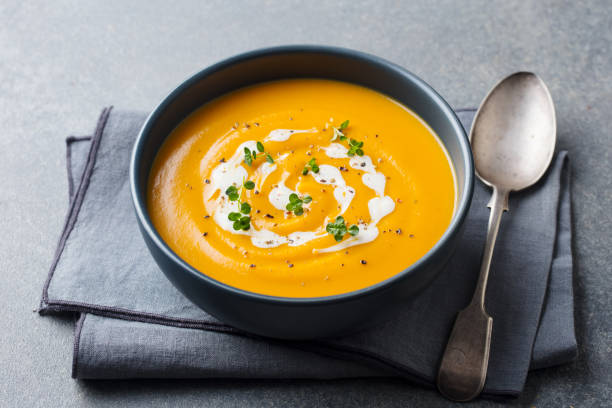 istock Pumpkin, carrot cream soup in a black bowl. Grey background. 1177028947