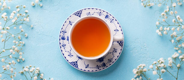 istock Cup of tea with fresh flowers on blue background. Top view. Copy space. 1177029069